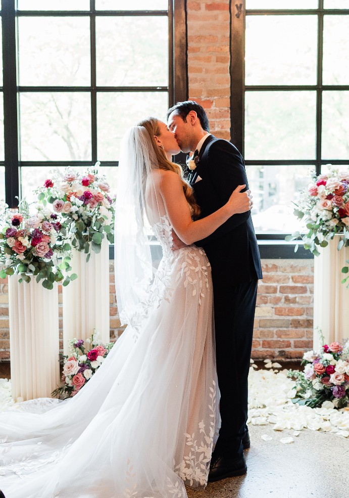 The founder of Cue the Moment kissing her husband at their wedding ceremony